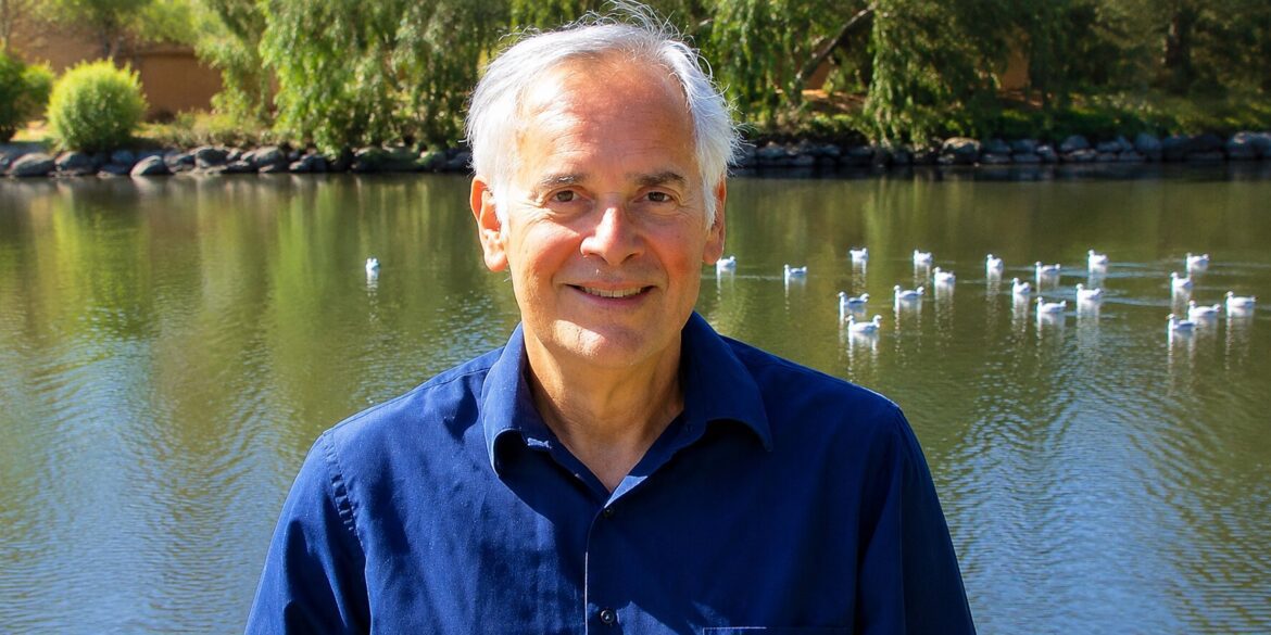 Ron Feldman smiling beside a lakeside pond, reflecting on resilience, personal growth, and his bridge career.