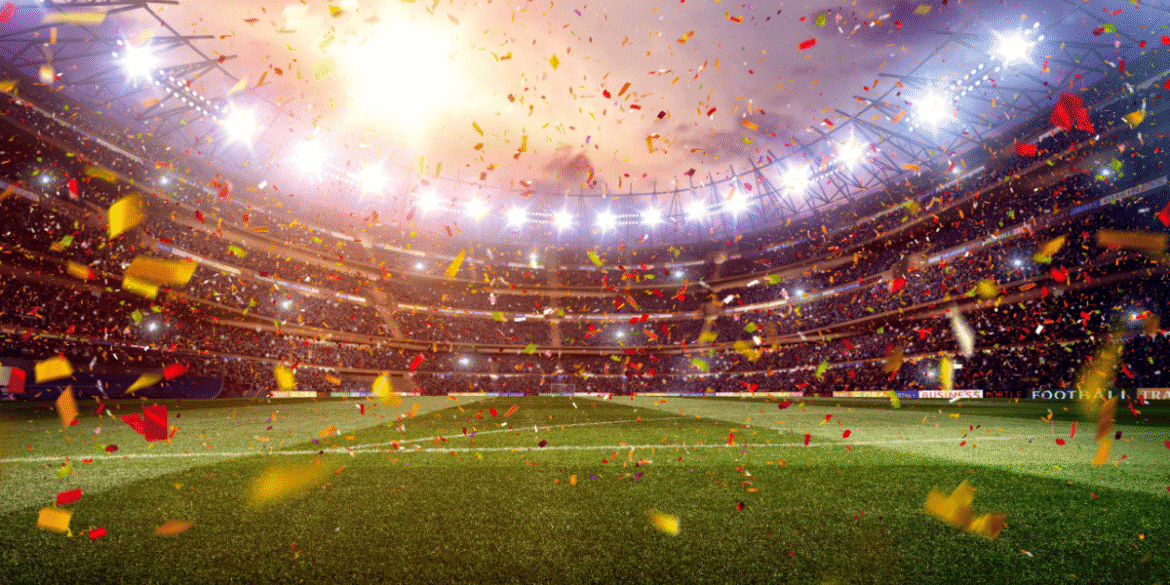 FIFA World Cup trophy beside a soccer ball on a grass field.