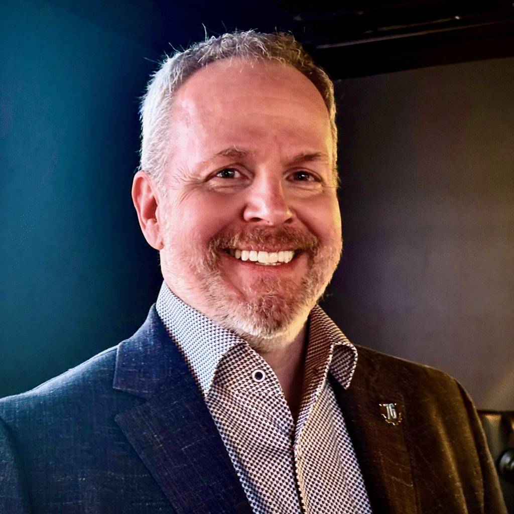 Brad Williams smiling in a blazer during a professional portrait.